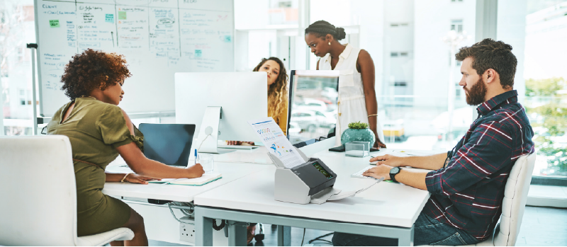 Team collaborating in a modern office with a desktop scanner from Woodhull, LLC, streamlining document management and enhancing productivity.