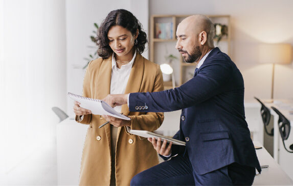 Two professionals reviewing documents in a modern office, highlighting Woodhull’s commitment to delivering tailored office technology solutions for business success.