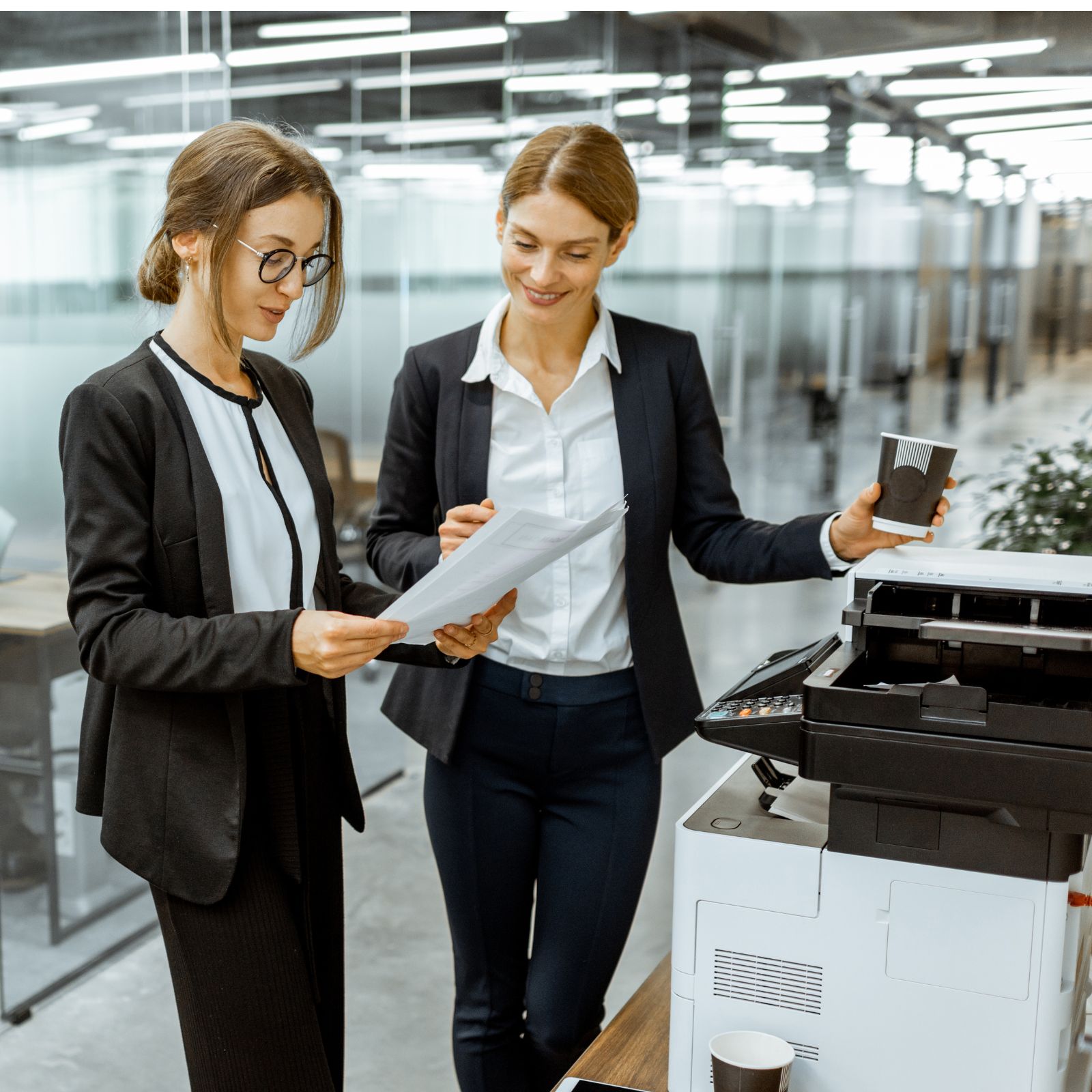 Two business professionals collaborating next to an office printer, demonstrating Woodhull’s efficient document management and printing solutions for modern workplaces.