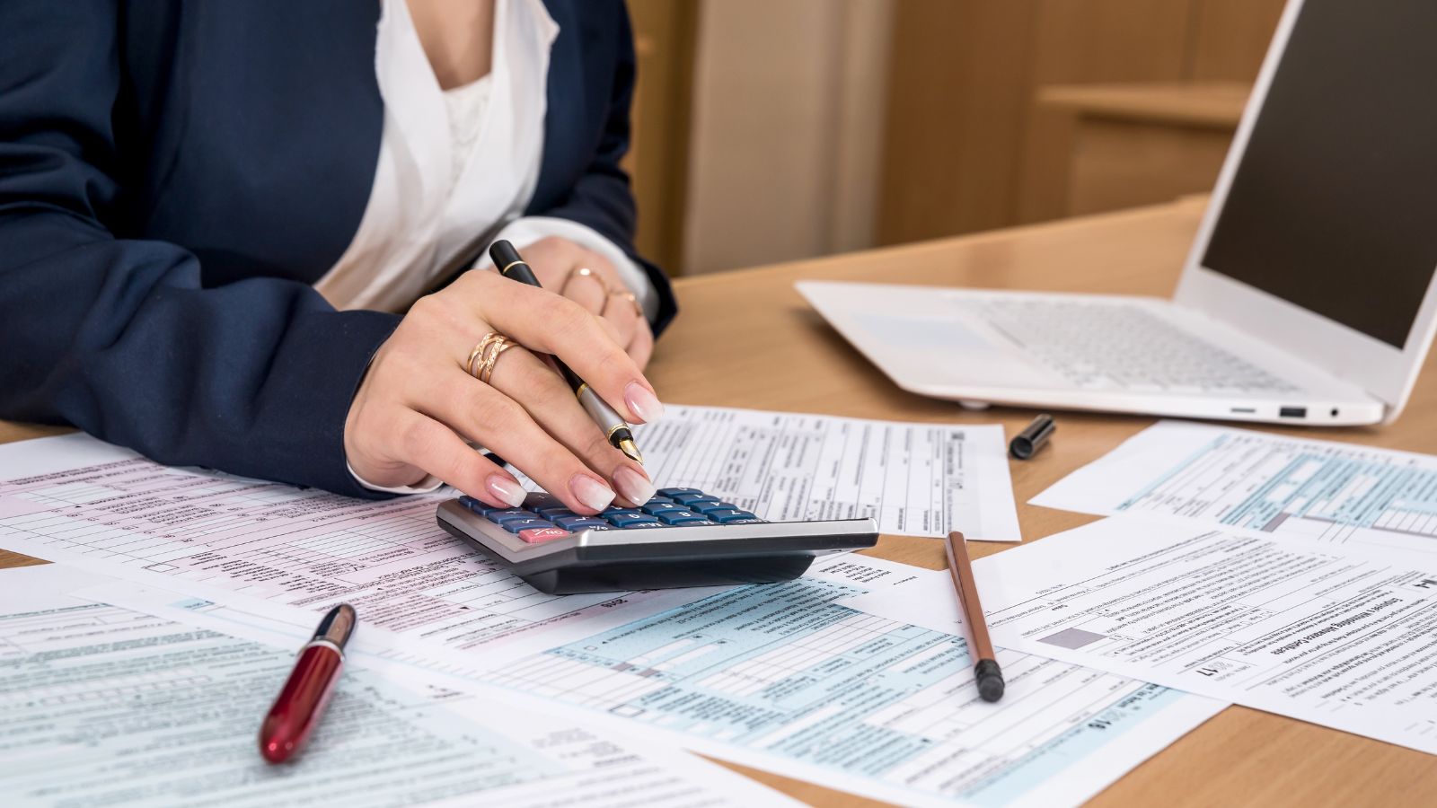 Business professional using a calculator to analyze documents, reflecting Woodhull's dedication to precision and efficiency in supporting WBENC-certified businesses.