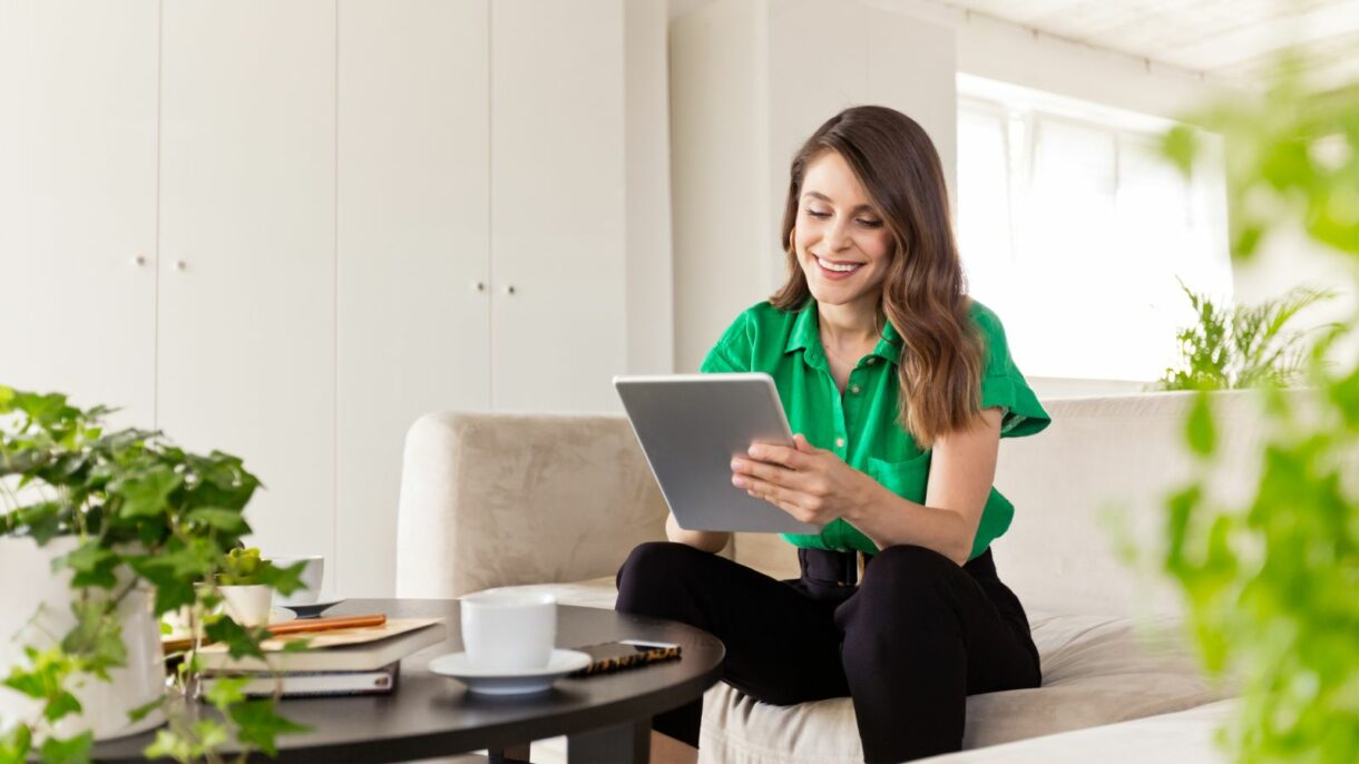 Smiling woman working on a tablet in a bright, modern space, representing Woodhull’s support for remote work and digital document solutions.